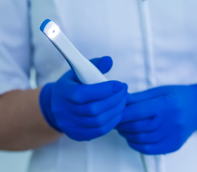 Gloved hands holding a thin white intraoral camera