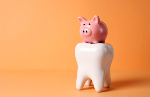 Pink piggy bank on large model tooth with orange background