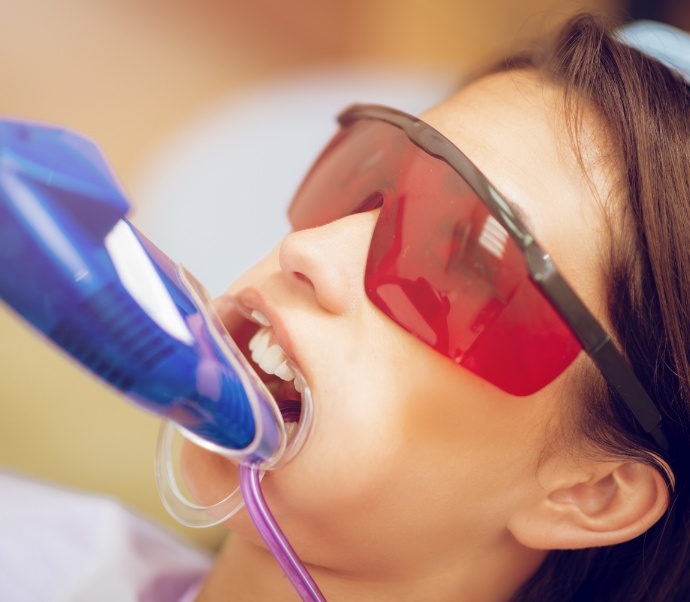 Young woman in dental chair having fluoride applied to her teeth