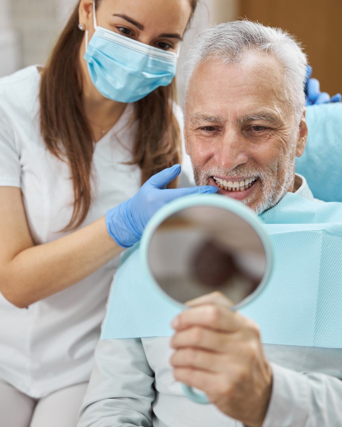 Patient admiring his treatment results sitting next to dentist