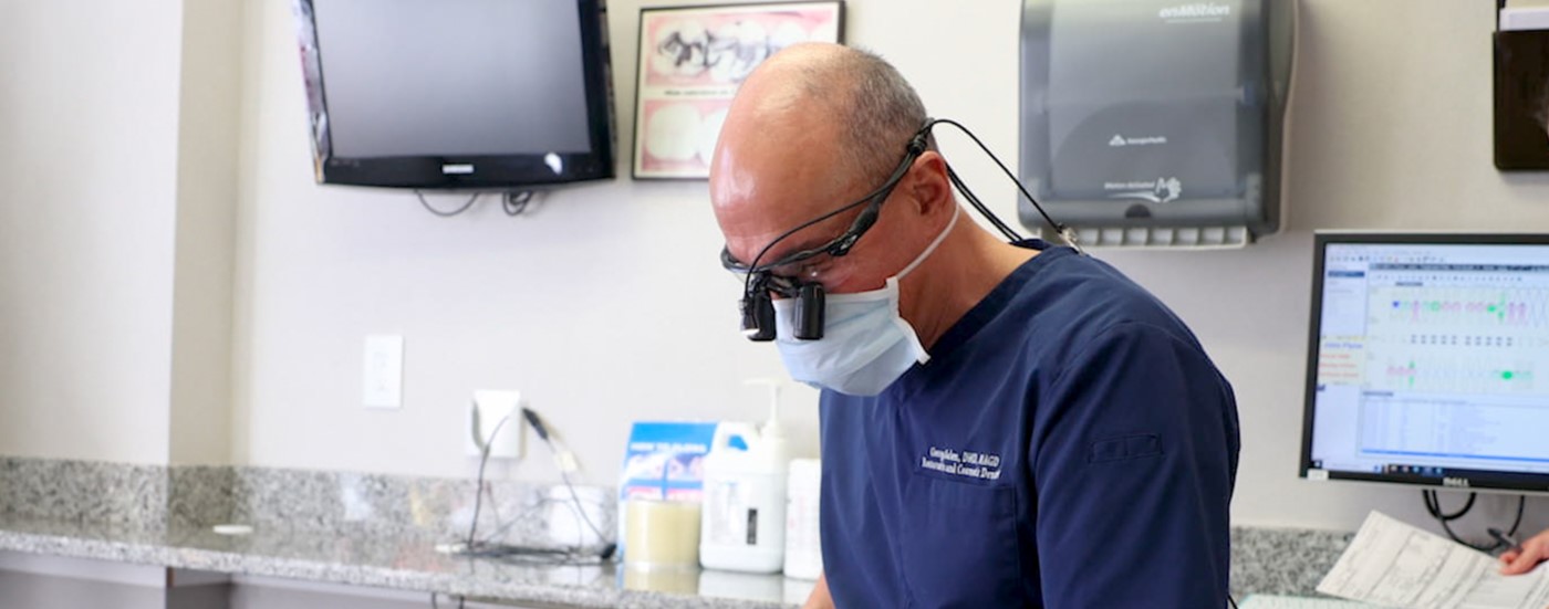 Dentist wearing dental binoculars while treating a patient