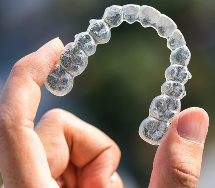 Hand holding an Invisalign clear aligner in Braintree