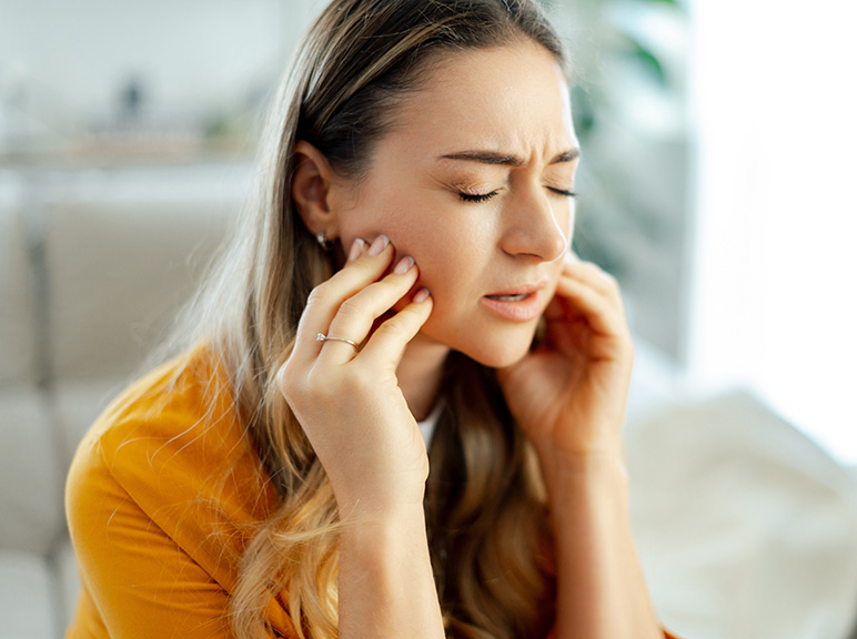 Benefit Image twenty Woman holding her jaw in pain, suggesting toothache or jaw discomfort.