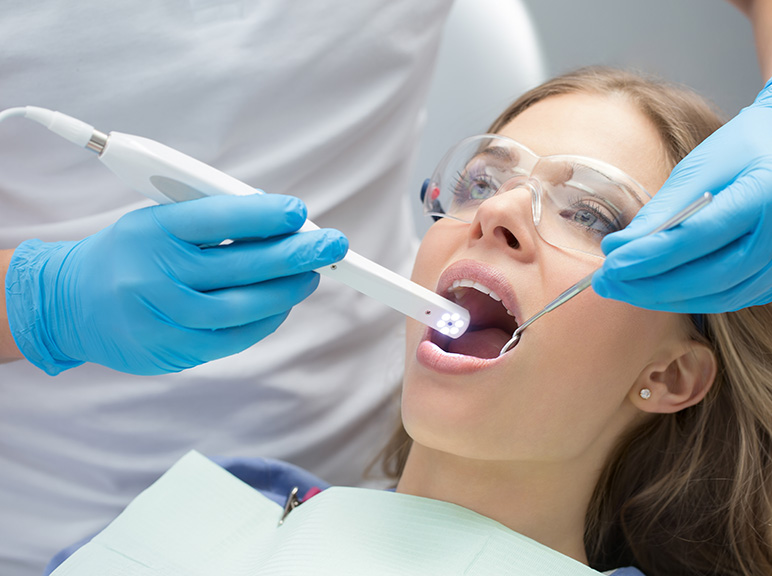 Intraoral Camera Dental professional examining a patient’s teeth with dental tools and protective eyewear.